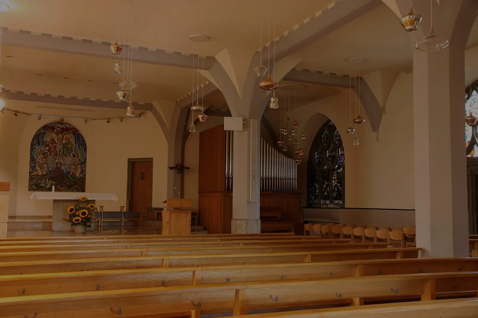 Kirchenraum im Kerzenschein mit Kreuz am Altar